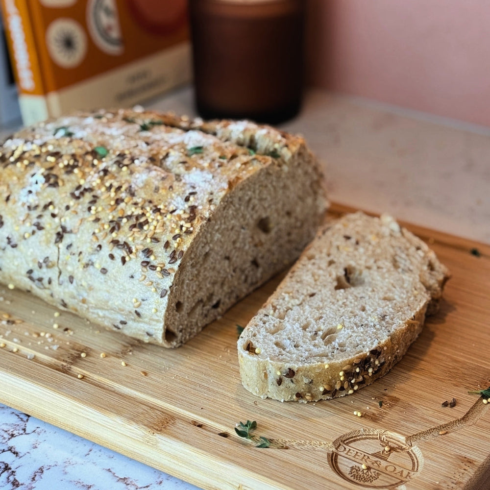 Loaf of bread with a slice cut, on a wooden cutting board with a blurred background.